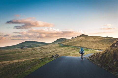 Senior cycling on road with mountains in distance